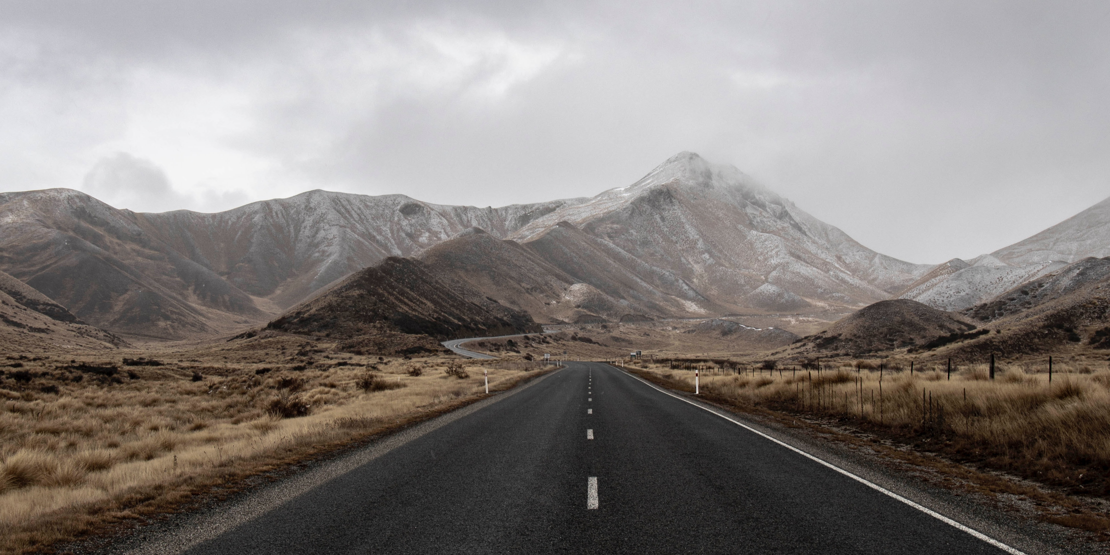 An empty road heading towards a rainy mountain